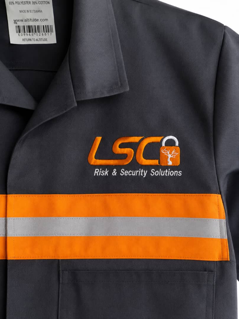 Dark safety workwear branded LSC Risk and Security Solutions with orange reflective trim.