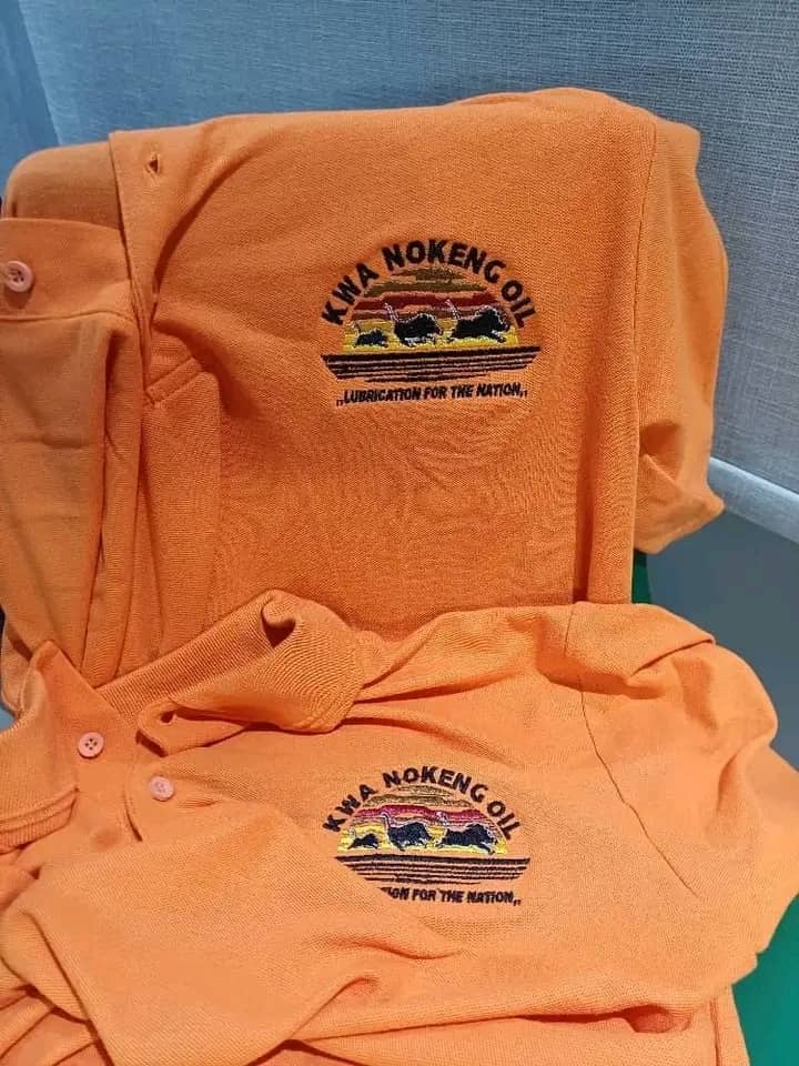 Finished orange polo shirts with a multicolour embroidered organisational crest.