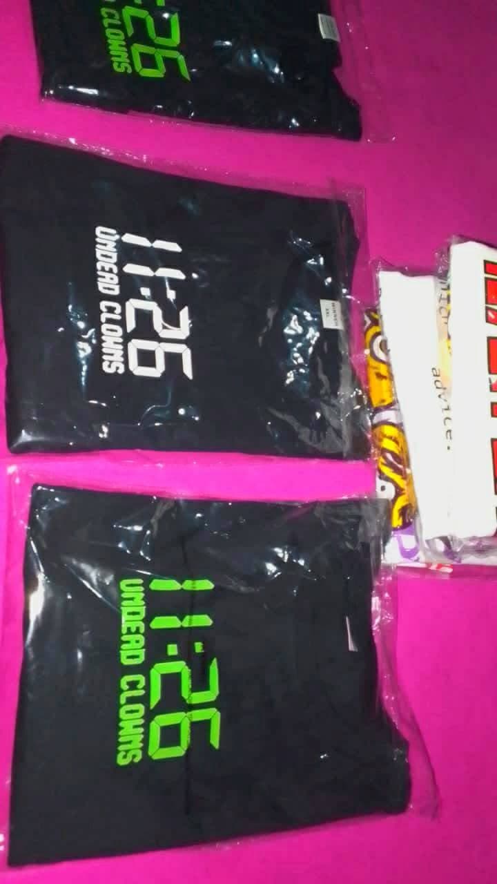 Packaged black Undead Clowns T-shirts showing 11:26 artwork in white and neon green.