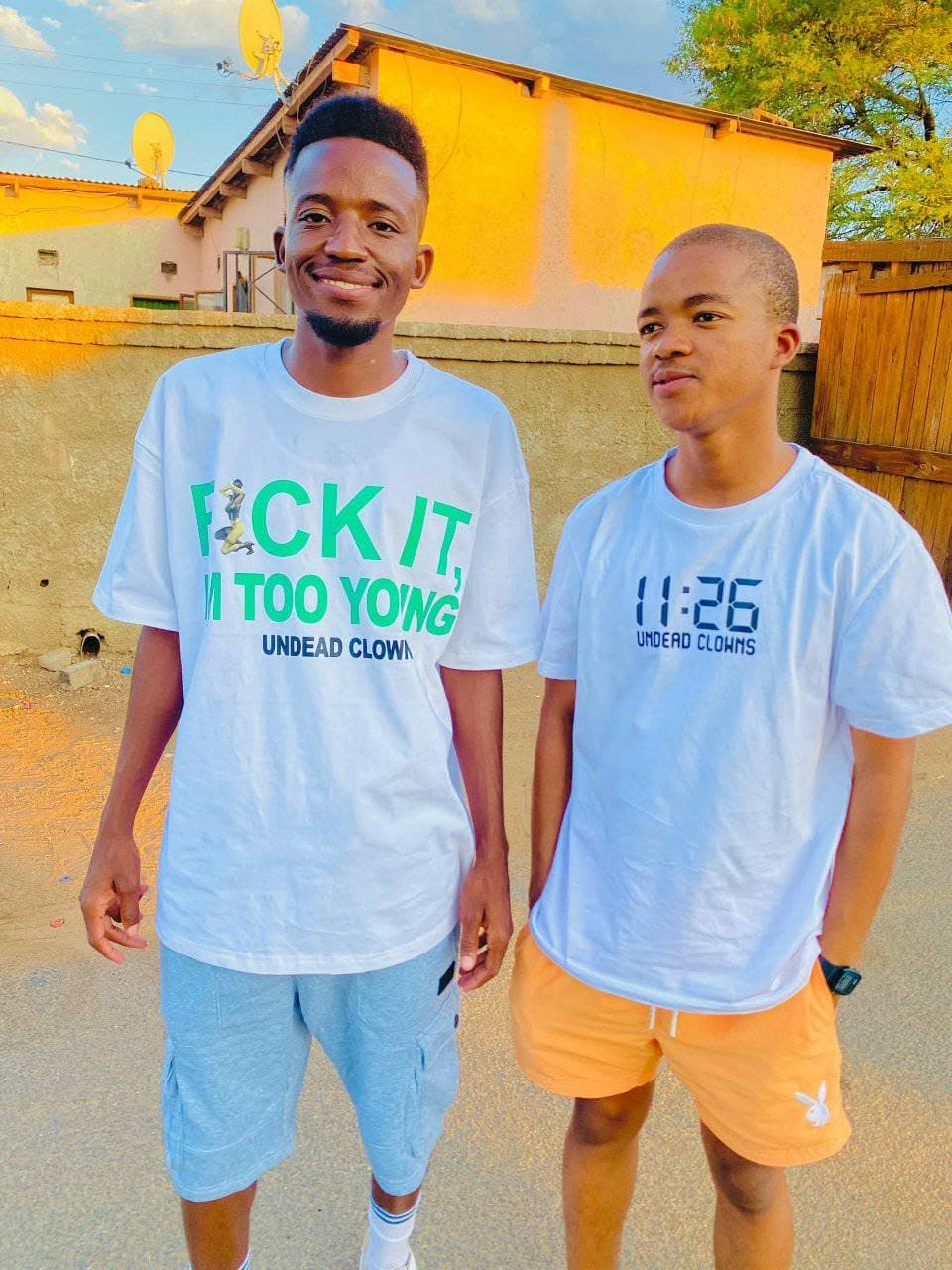 Two people wearing white Undead Clowns T-shirts with different front graphics.